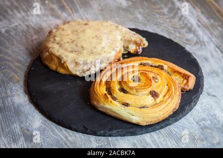 Schmerzen aux Rosinen auf Anzeige auf einem rustikalen Holztisch. Ein Schmerz aux Rosinen ist ein typisches Frühstück mit französischem Gebäck, viennoiserie Stil, aus Spirale doug Stockfoto