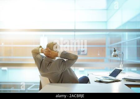 Rückansicht Blickrichtung der Geschäftsmann im Büro Stuhl gelehnt mit Arme hinter Kopf Stockfoto