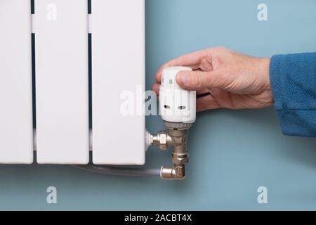 Hand Herunterdrehen der Temperatur auf die TRV Kühler thermostat Ventil Stockfoto