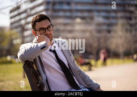 Junge müde Geschäftsmann ruht in der Park nach der Arbeit. Stockfoto