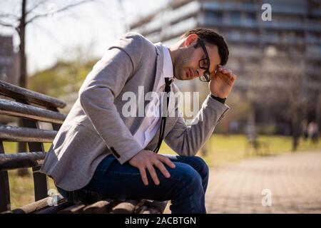 Junge müde Geschäftsmann ruht in der Park nach der Arbeit. Stockfoto