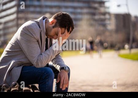 Junge Unternehmer ist sitzt im Park nach abgefeuert wurde. Er ist deprimiert. Stockfoto