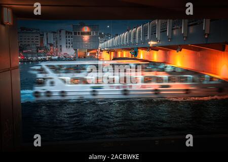 Istanbul, Türkei: November 30, 2019: Die Stadt Fähre vorbei unter der Galata Brücke, Langzeitbelichtung Bild während der Dämmerung Stockfoto