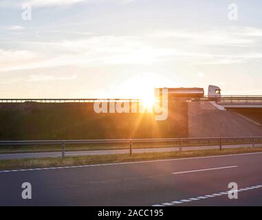 Lkw-Fahrer auf einem großen Lkw mit einem Tanker trägt Cargo vor dem Hintergrund eines sonnigen Sonnenuntergang, Kopie Raum Stockfoto