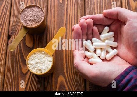 Mann hält Aminosäure Kapseln auf dem Hintergrund schaufeln Protein Stockfoto