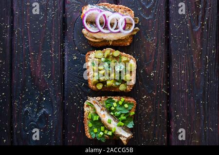 Verschiedene Sandwiches mit Gemüse, Pflanzen und Fische auf einem schwarzen Hintergrund Stockfoto