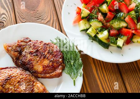 Gegrilltes Fleisch mit Dill und Salat mit Gurken und Tomaten Stockfoto