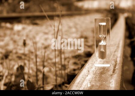 Transparente Sanduhr stehen auf dem alten rostigen Schiene in sepia Ton, Zeit Konzept Stockfoto