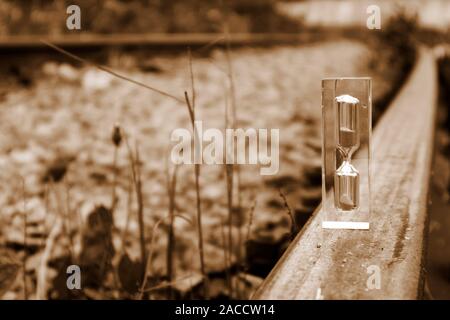 Transparente Sanduhr stehen auf dem alten rostigen Schiene in sepia Ton, Zeit Konzept Stockfoto