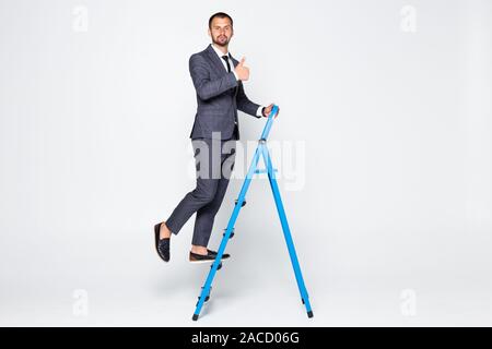 In voller Länge Porträt der Geschäftsmann mit Daumen nach oben klettern eine Leiter auf weißem Hintergrund Stockfoto