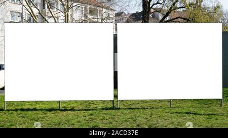 Zwei leere Leere Anzeigentafeln nebeneinander auf städtischen Grünflächen am Straßenrand Stockfoto