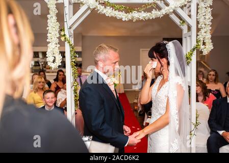 Eine Braut weint, während sie drinnen bei einer traditionellen englischen Hochzeitszeremonie im Manor, B&B, Hotel in Cheadle Stoke in Trent Staffordshire heiratet Stockfoto