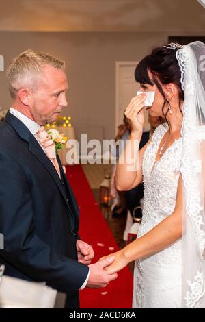 Eine Braut weint, während sie drinnen bei einer traditionellen englischen Hochzeitszeremonie im Manor, B&B, Hotel in Cheadle Stoke in Trent Staffordshire heiratet Stockfoto