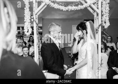 Eine Braut weint, während sie drinnen bei einer traditionellen englischen Hochzeitszeremonie im Manor, B&B, Hotel in Cheadle Stoke in Trent Staffordshire heiratet Stockfoto