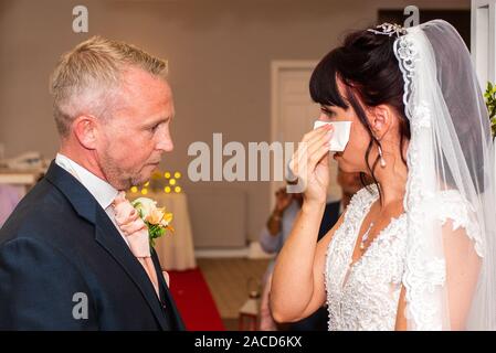 Eine Braut weint, während sie drinnen bei einer traditionellen englischen Hochzeitszeremonie im Manor, B&B, Hotel in Cheadle Stoke in Trent Staffordshire heiratet Stockfoto