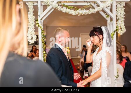 Eine Braut weint, während sie drinnen bei einer traditionellen englischen Hochzeitszeremonie im Manor, B&B, Hotel in Cheadle Stoke in Trent Staffordshire heiratet Stockfoto