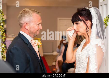 Eine Braut weint, während sie drinnen bei einer traditionellen englischen Hochzeitszeremonie im Manor, B&B, Hotel in Cheadle Stoke in Trent Staffordshire heiratet Stockfoto