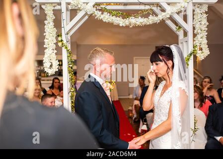 Eine Braut weint, während sie drinnen bei einer traditionellen englischen Hochzeitszeremonie im Manor, B&B, Hotel in Cheadle Stoke in Trent Staffordshire heiratet Stockfoto