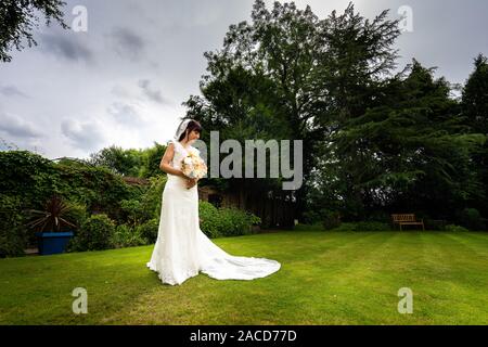 Eine Braut posiert für sie nach den Bildern der Zeremonie in den Gärten des Manor Hotels, B&B in Cheadle, Stoke on Trent, Staffordshire, Hochzeitstag Stockfoto