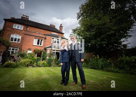 Ein Bräutigam, Vater posiert mit seinem kleinen Jungen, nachdem er geheiratet hat in The Manor Gardens, Hotel, B&B in Cheadle, Stoke on Trent, Staffordshire, Hochzeitstag Stockfoto