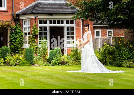 Eine Braut posiert für sie nach den Bildern der Zeremonie in den Gärten des Manor Hotels, B&B in Cheadle, Stoke on Trent, Staffordshire, Hochzeitstag Stockfoto