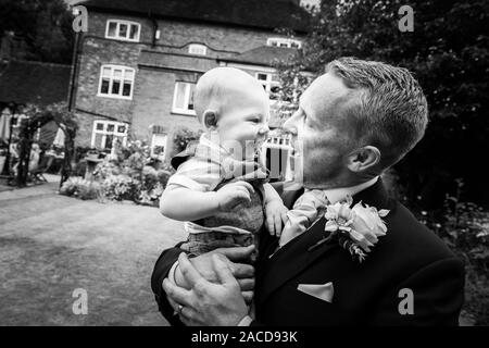 Ein Bräutigam, Vater posiert mit seinem kleinen Jungen, nachdem er geheiratet hat in The Manor Gardens, Hotel, B&B in Cheadle, Stoke on Trent, Staffordshire, Hochzeitstag Stockfoto