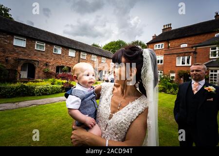 Eine Braut, Mutter posiert mit ihrem kleinen Jungen, nachdem sie geheiratet hat in The Manor Gardens, Hotel, B&B in Cheadle, Stoke on Trent, Staffordshire, Hochzeitstag Stockfoto