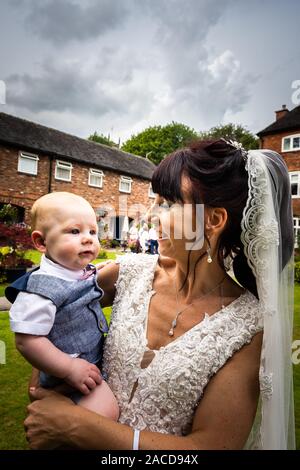 Eine Braut, Mutter posiert mit ihrem kleinen Jungen, nachdem sie geheiratet hat in The Manor Gardens, Hotel, B&B in Cheadle, Stoke on Trent, Staffordshire, Hochzeitstag Stockfoto