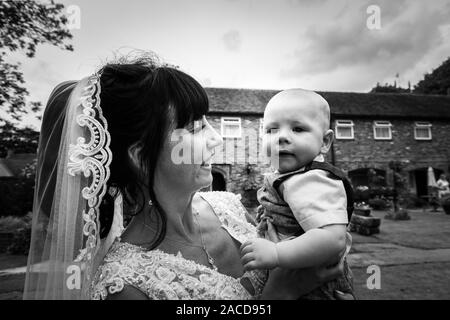 Eine Braut, Mutter posiert mit ihrem kleinen Jungen, nachdem sie geheiratet hat in The Manor Gardens, Hotel, B&B in Cheadle, Stoke on Trent, Staffordshire, Hochzeitstag Stockfoto