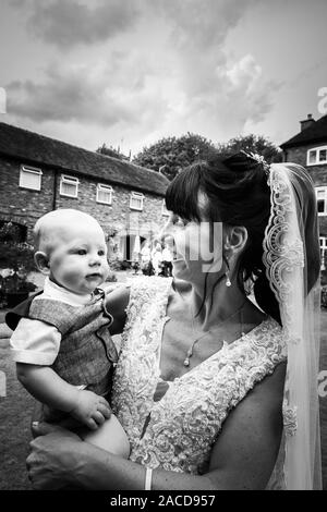 Eine Braut, Mutter posiert mit ihrem kleinen Jungen, nachdem sie geheiratet hat in The Manor Gardens, Hotel, B&B in Cheadle, Stoke on Trent, Staffordshire, Hochzeitstag Stockfoto