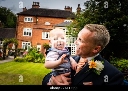 Ein Bräutigam, Vater posiert mit seinem kleinen Jungen, nachdem er geheiratet hat in The Manor Gardens, Hotel, B&B in Cheadle, Stoke on Trent, Staffordshire, Hochzeitstag Stockfoto