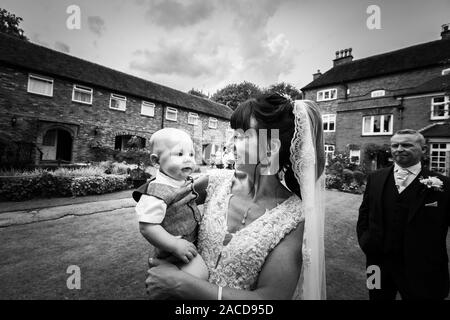 Eine Braut, Mutter posiert mit ihrem kleinen Jungen, nachdem sie geheiratet hat in The Manor Gardens, Hotel, B&B in Cheadle, Stoke on Trent, Staffordshire, Hochzeitstag Stockfoto