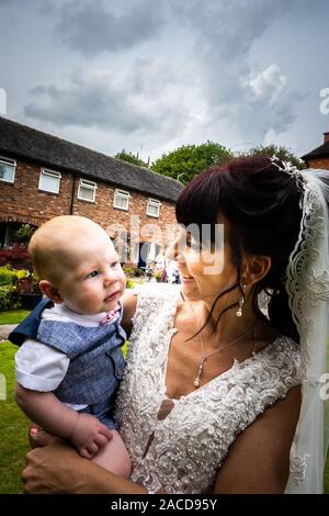 Eine Braut, Mutter posiert mit ihrem kleinen Jungen, nachdem sie geheiratet hat in The Manor Gardens, Hotel, B&B in Cheadle, Stoke on Trent, Staffordshire, Hochzeitstag Stockfoto