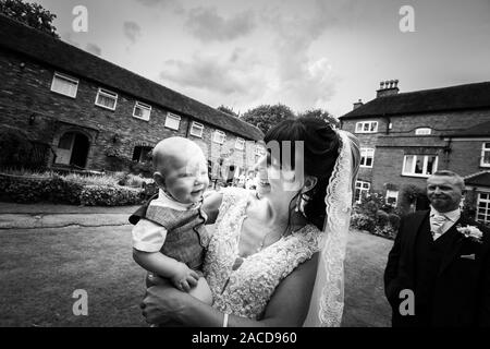 Eine Braut, Mutter posiert mit ihrem kleinen Jungen, nachdem sie geheiratet hat in The Manor Gardens, Hotel, B&B in Cheadle, Stoke on Trent, Staffordshire, Hochzeitstag Stockfoto