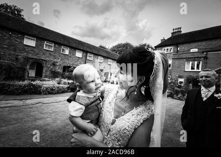 Eine Braut, Mutter posiert mit ihrem kleinen Jungen, nachdem sie geheiratet hat in The Manor Gardens, Hotel, B&B in Cheadle, Stoke on Trent, Staffordshire, Hochzeitstag Stockfoto