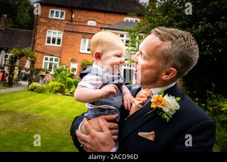 Ein Bräutigam, Vater posiert mit seinem kleinen Jungen, nachdem er geheiratet hat in The Manor Gardens, Hotel, B&B in Cheadle, Stoke on Trent, Staffordshire, Hochzeitstag Stockfoto