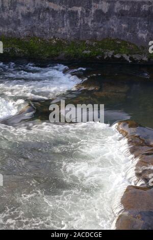 Das Flussbett mit sehr klarem Wasser fließt über große Unterwasser Felsen, die zu einem kleinen Stromschnellen in der Altstadt von Bridgend in South Wales. Stockfoto