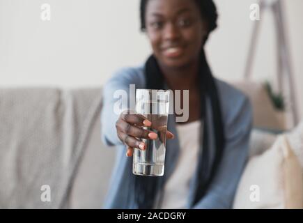 Schwarz Girl Holding Glas Mineralwasser bietet es Auf der Kamera Stockfoto