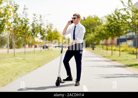 Geschäftsmann mit Roller Aufruf auf dem Smartphone Stockfoto
