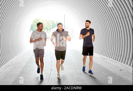 Männliche Freunde mit Ohrhörer laufen im Freien