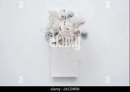 Weihnachten mock up von getrockneten Blumenstrauß aus Baumwolle Blumen, Kegel und Schneeflocken in Weiß-Paket mit Platz für Ihren Text. Grußkarte Design für Poster Stockfoto