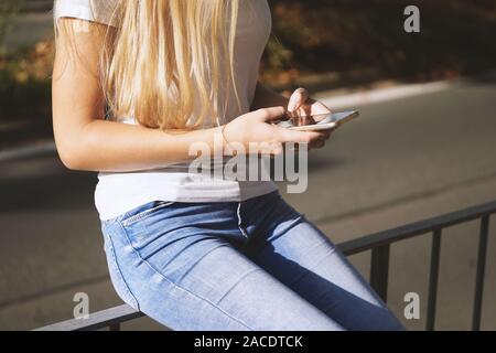 Mittelteil der unkenntlich junge Frau mit ihrem Smartphone oder Handy außerhalb der Stadt. Stockfoto