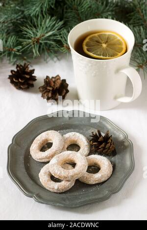 Traditionelle rumänische oder moldawische Kekse aus Mürbeteig und eine Tasse Tee auf dem Hintergrund eines Winterdekors. Stockfoto