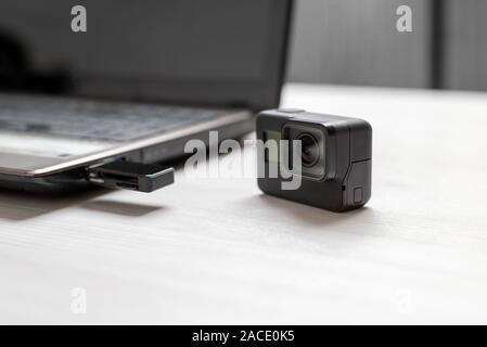 Action Kamera neben dem Laptop. Mini-SD-Karte in den Card Reader an den USB-Port. Das Konzept der Übertragung von Fotos und Videos auf den Computer. Stockfoto