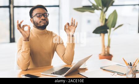 Ruhige schwarze Kerl meditieren während Hausaufgaben Stockfoto