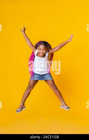 Süße kleine Afro girl Jumping über Gelb studio Hintergrund Stockfoto