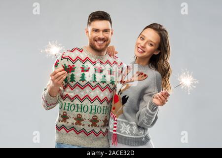 Glückliches Paar in Weihnachten Pullover mit Wunderkerzen Stockfoto