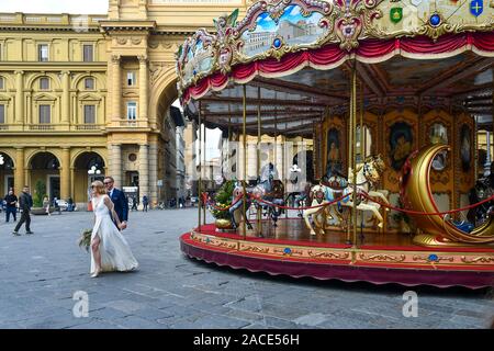 Ein Paar der Jungvermählten in Platz der Republik im historischen Zentrum von Florenz mit dem alten Karussell und dem Arc de Triumph, Toskana, Italien Stockfoto