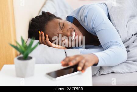 Schwarze Frau mit Kopfschmerzen aufwachen im Bett zu Hause. Stockfoto