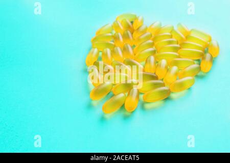 Große medizinische Kapseln und Tabletten - Vitamine und Zusatzstoffe auf blauem Hintergrund liegen in der Form eines Herzens. Kopieren Sie Platz. Close Up. Selektiver Fokus Stockfoto